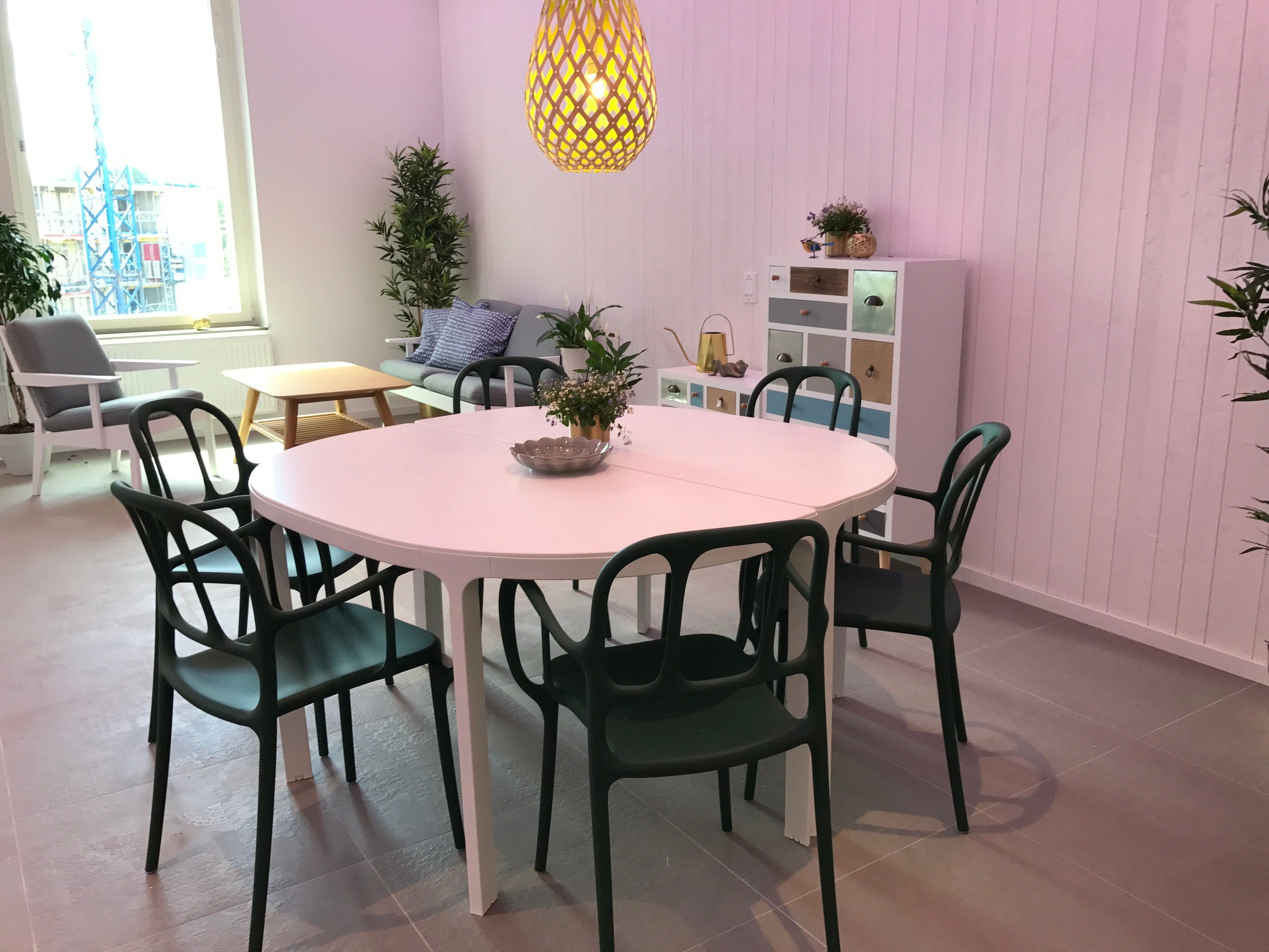 Modern matplats med runt bord, svarta stolar, dekorativa växter och mysig sittplats.