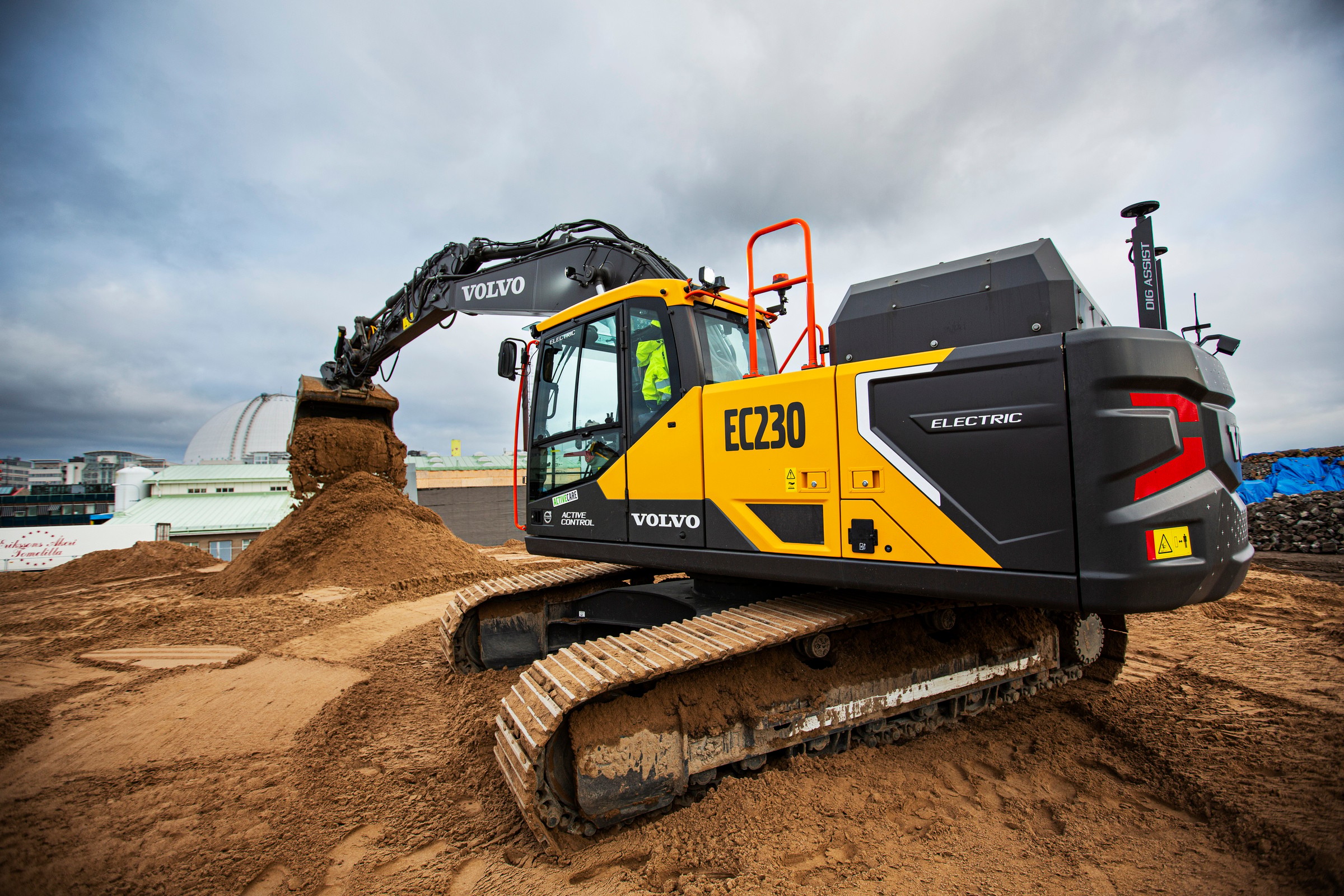 Volvo Construction Equipments nya helelektriska grävmaskin EC230 ska minska utsläppen av CO2. Elektrisk Volvo EC230-grävmaskin som flyttar sand på en byggarbetsplats under en molnig himmel.