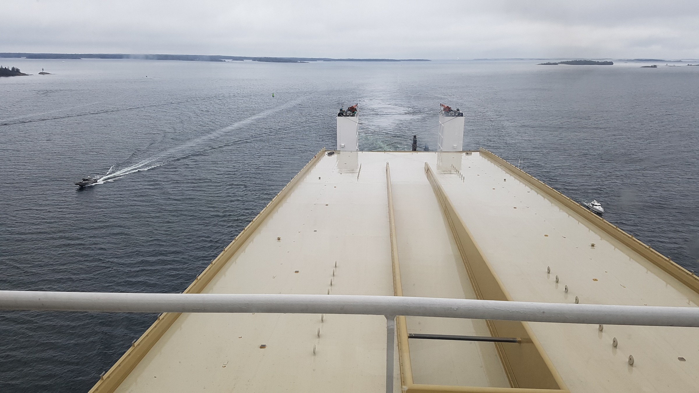 Den gyllene bron på sin båtfärd genom Stockholms skärgård 11 mars 2020. Utsikt från ett skeppsdäck med vy över lugna vatten och avlägsna öar, med båtar som passerar förbi.