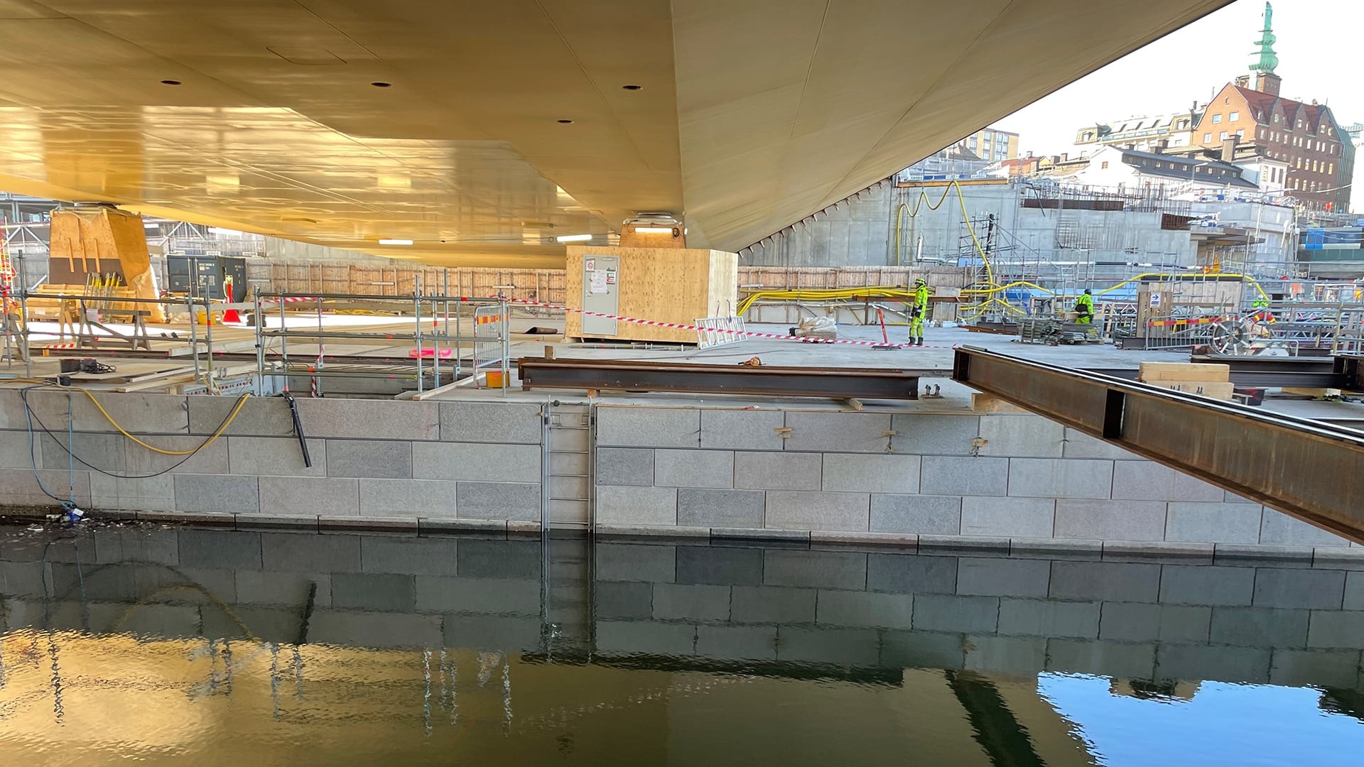 Den guldfärgade undersidan på Slussbron speglar sig vacker i den vattenfyllda slusskanalen.
