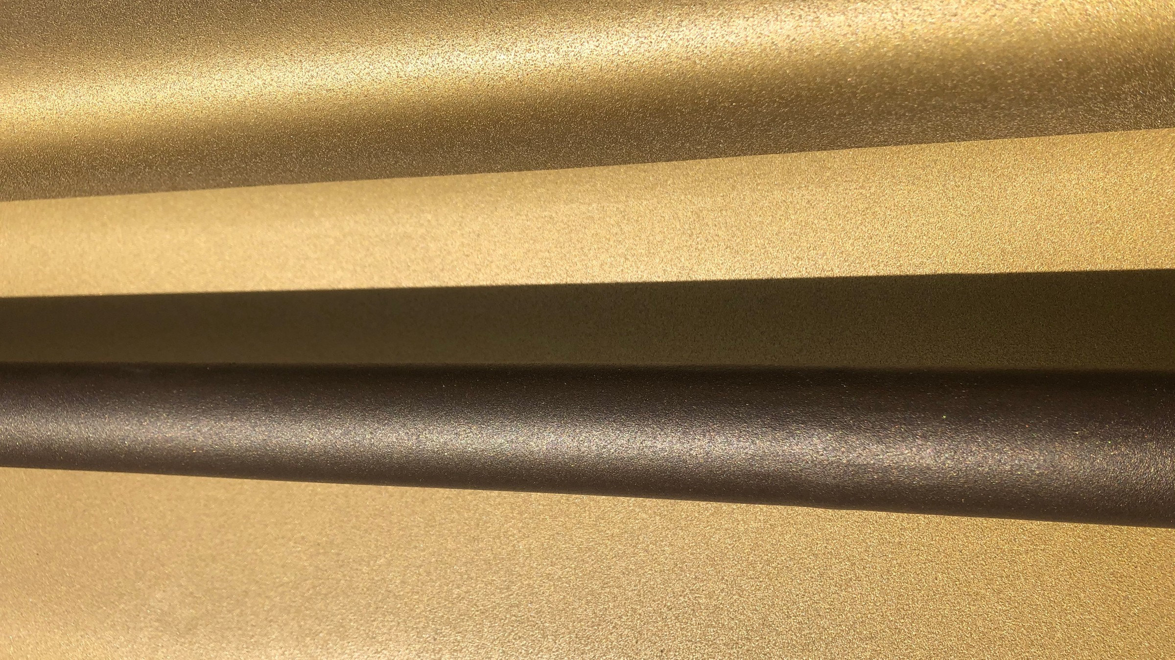Handledaren och räcket är specialtillverkade. Närbild av metalliska guld- och bronstexturerade ytor med kontrasterande horisontella linjer.