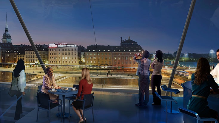 Visionsbild: Utsikt över vattentorget och Gamla stan från byggnaden på Södermalmstorg (Källa: White arkitekter) Människor njuter av en nattlig stadsutsikt från en modern, inglasad utsiktsplattform.