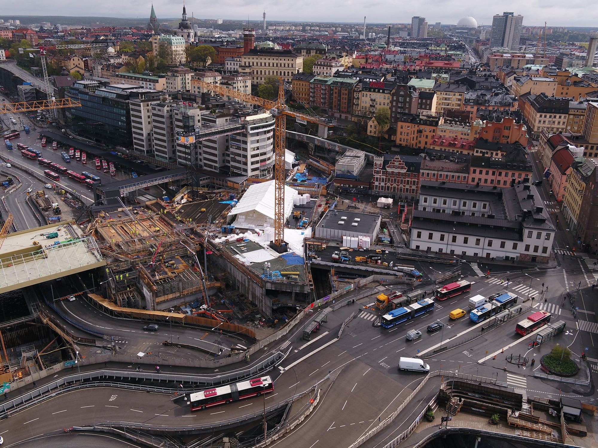 Flygvy över ett livligt stadsområde med byggarbetsplats och trafik i en europeisk stad.