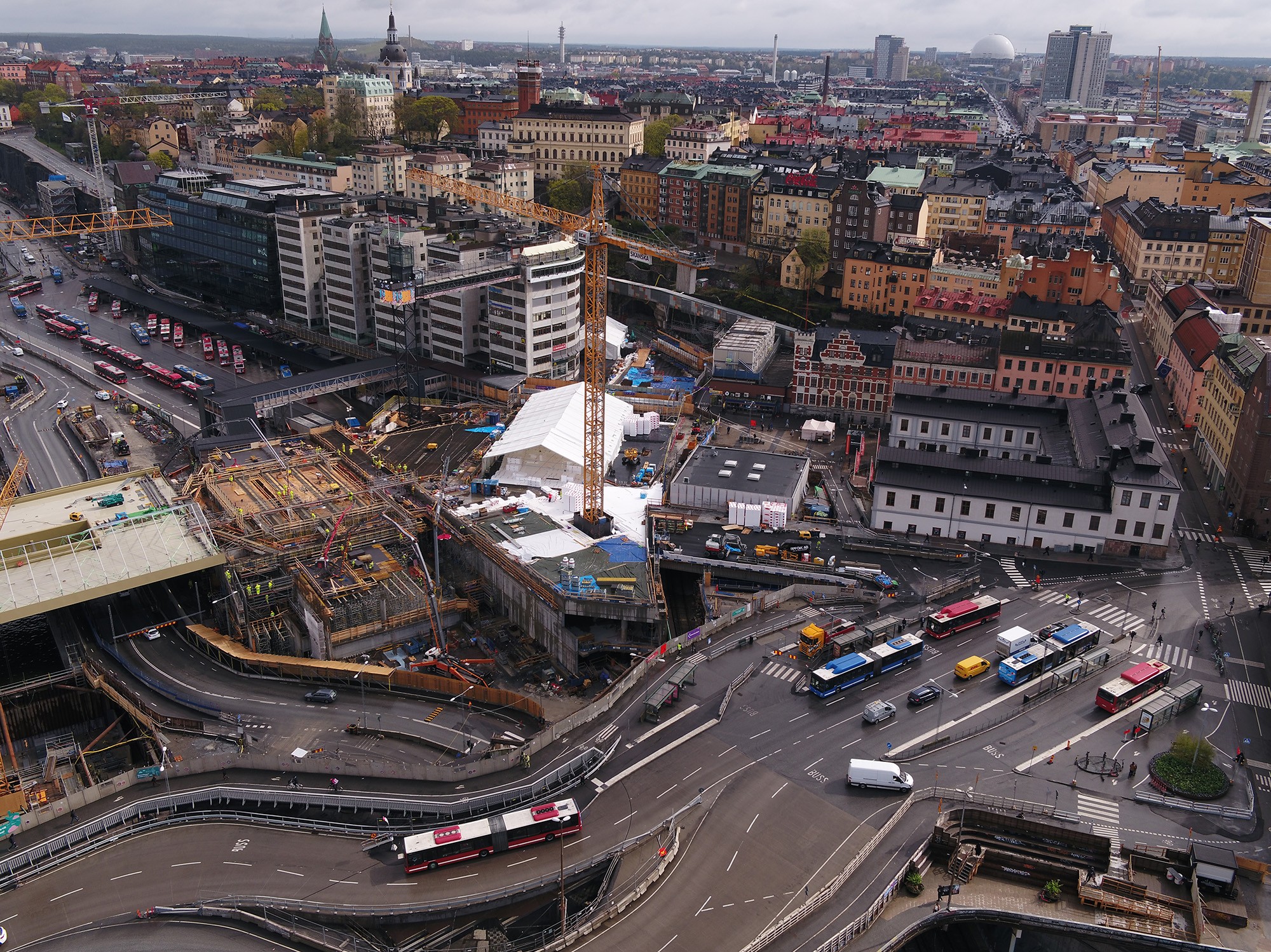 Vy över brofästet mot Södermalm. Flygvy över ett livligt stadsområde med byggarbetsplats och trafik i en europeisk stad.