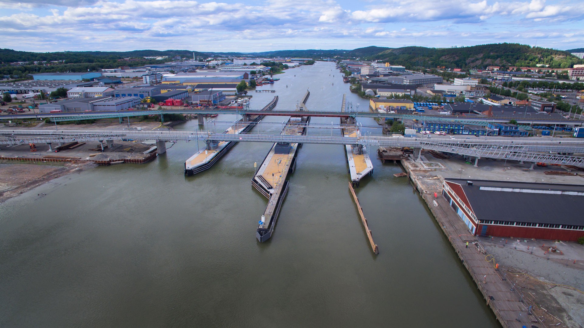Södra Marieholmsbron togs i bruk runt påsken 2016. Flygvy över en livlig industrihamn med flera kajer och en bro som sträcker sig över vattenvägen.