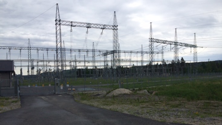 Det färdiga ställverket, 400 kilovolt. Elektrisk kraftstation med högspänningsmaster och ledningar mot en bakgrund av molnig himmel.