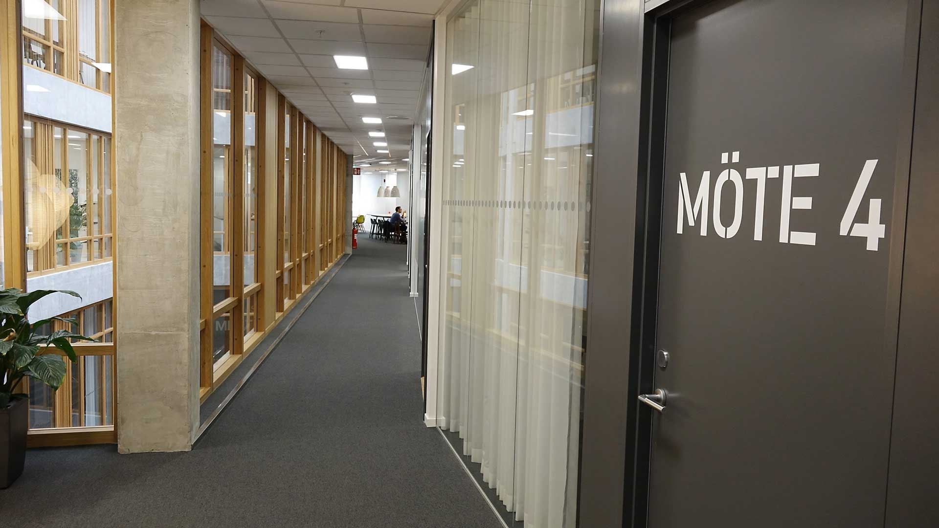 Boxplan Korridor med stora fönster och en dörr märkt "Möte 4," som leder till ett mötesrum.