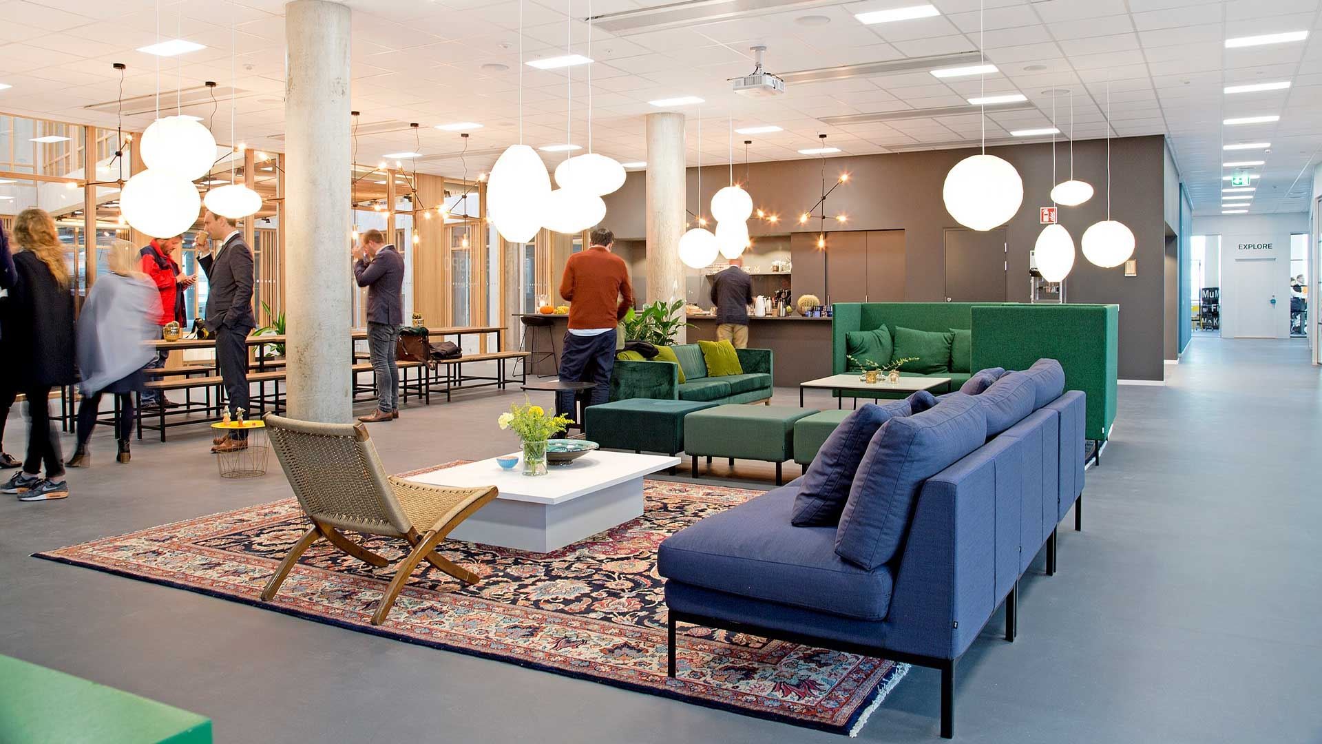 Studio meetingpoint by altitude Modern kontorslounge med färgglada soffor, mönstrad matta, hänglampor och människor som umgås.