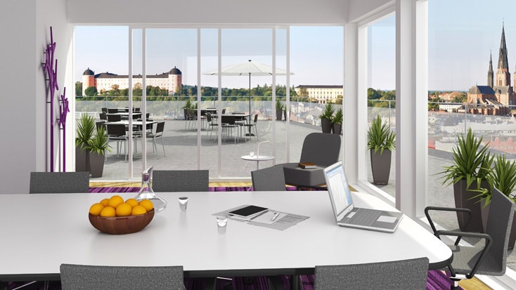 Uppsala Entré Modern konferensrum med stora fönster, utsikt över terrassen, laptop och skål med apelsiner på bordet.