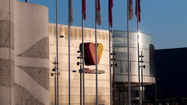 Exteriörvy av Valencia Forum med flaggor, med en distinkt hjärtformad logotyp.