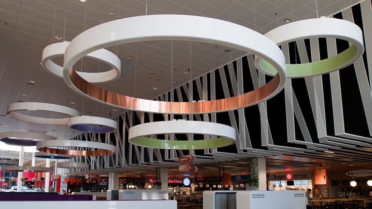 Moderna takrosetter i en food court med geometriska väggmönster och olika restaurangskyltar.