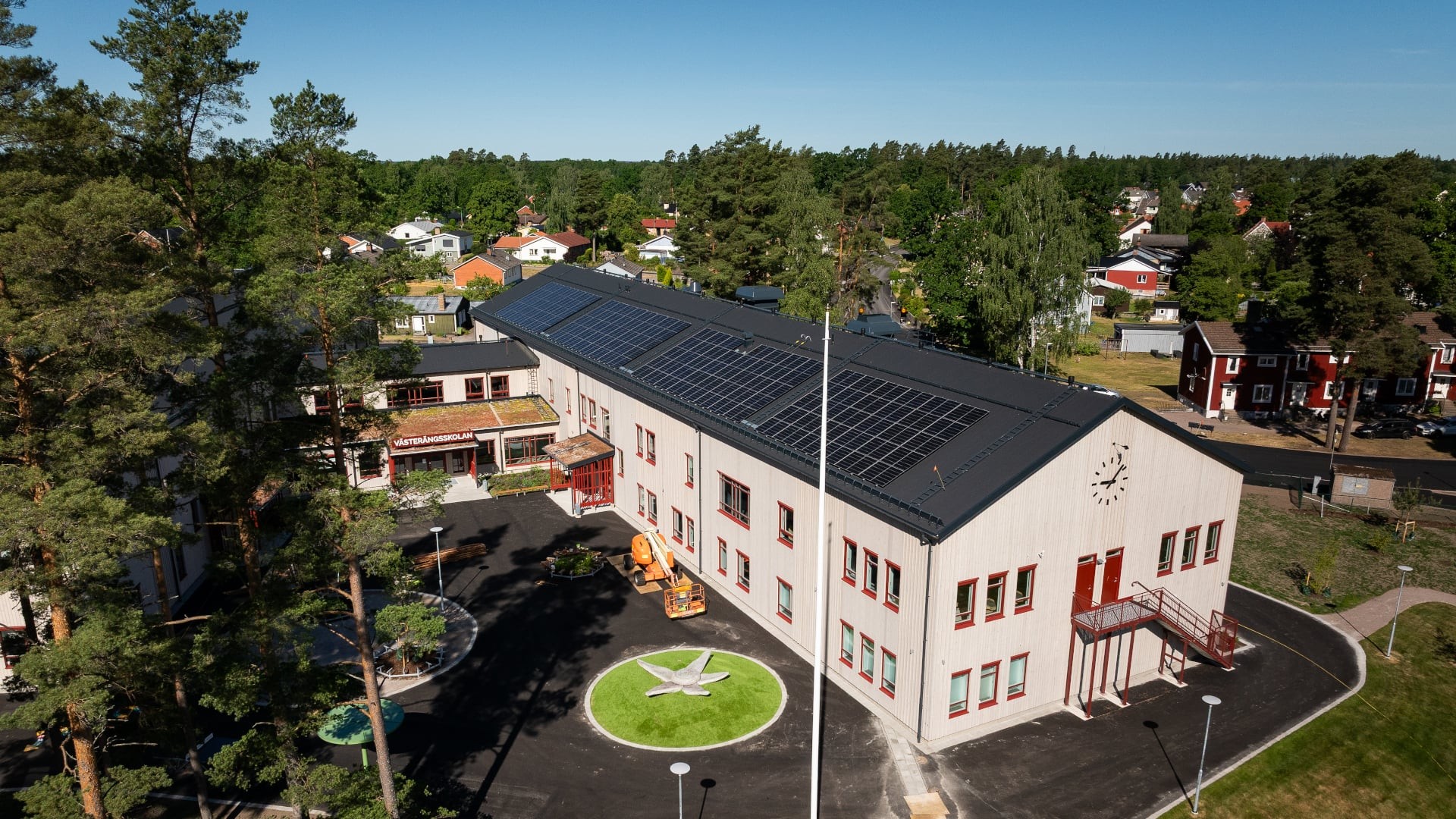 Flygbild över Västerängsskolan i Nybro med solpaneler på taken och grön utemiljö.