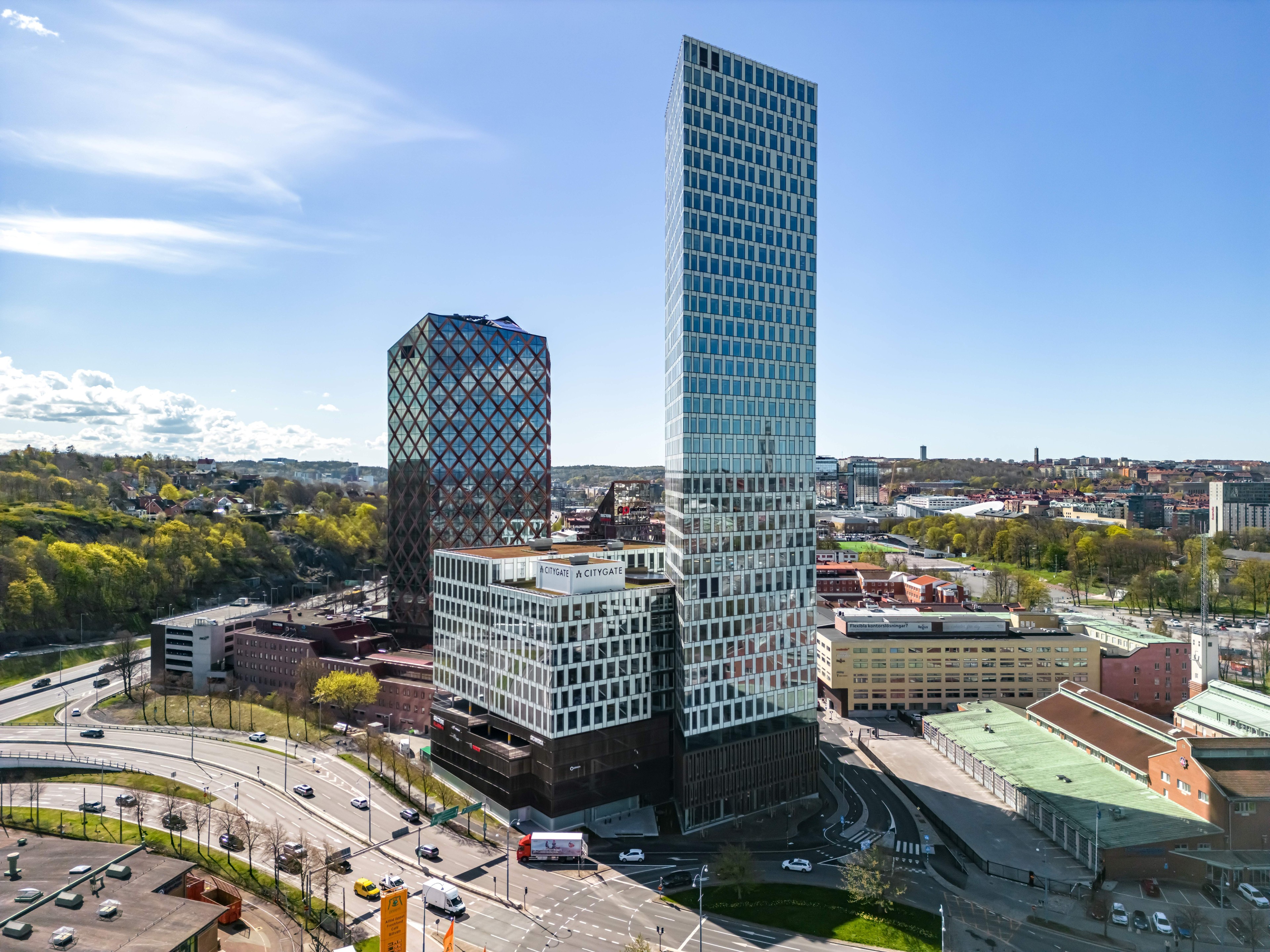 Moderna höga kontorsbyggnader med glasfasader i en stadsbild under en klar blå himmel.