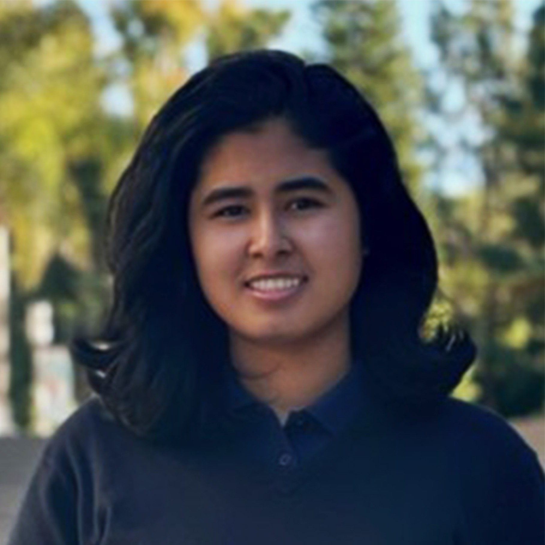 Woman with Medium Black Hair Outdoors in Casual Navy Shirt Person with medium-length black hair wearing a dark blue shirt outdoors with trees.
