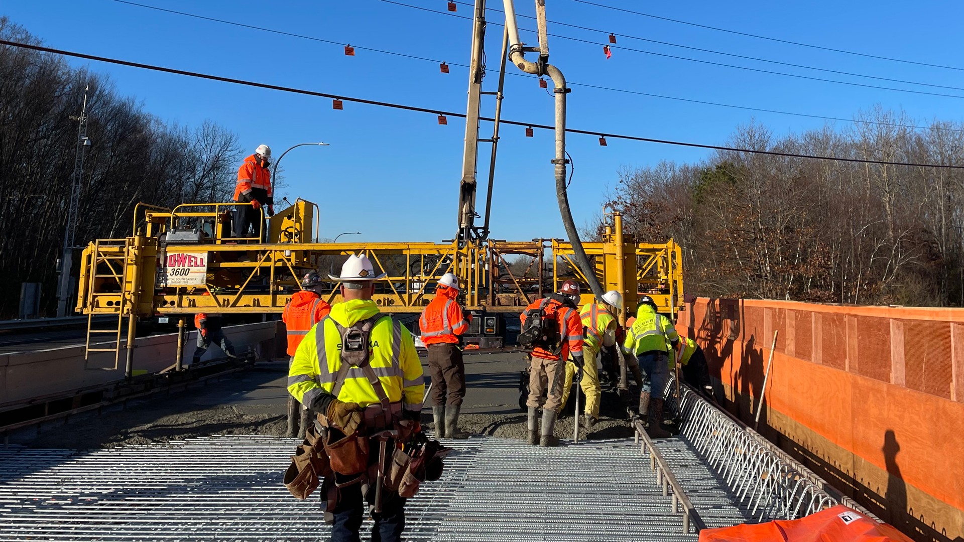 Construction workers pouring concrete on bridge deck with machinery Construction workers pouring concrete on a bridge with heavy machinery and rebar.