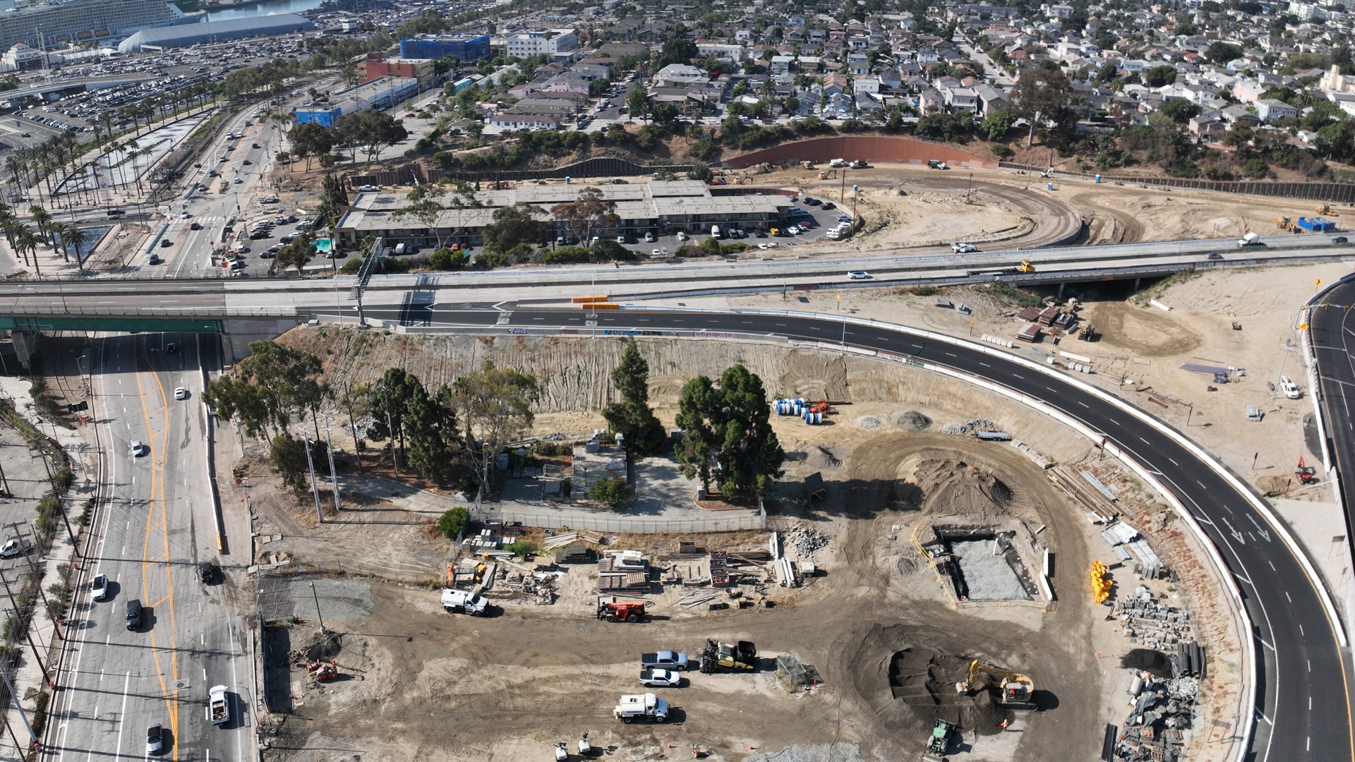 Aerial view of highway construction site with heavy machinery and nearby residential area.