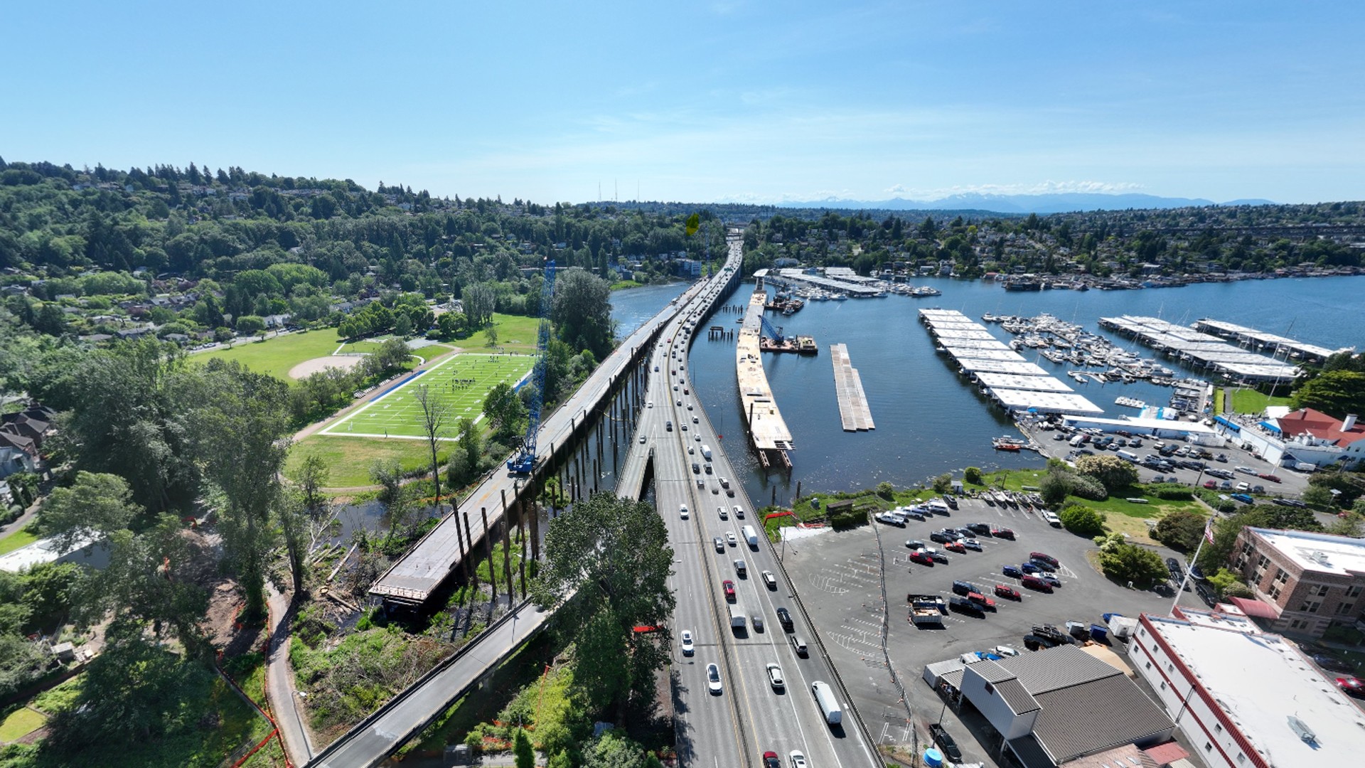 Aerial view of a busy bridge over water with boats and greenery on a clear sunny day.