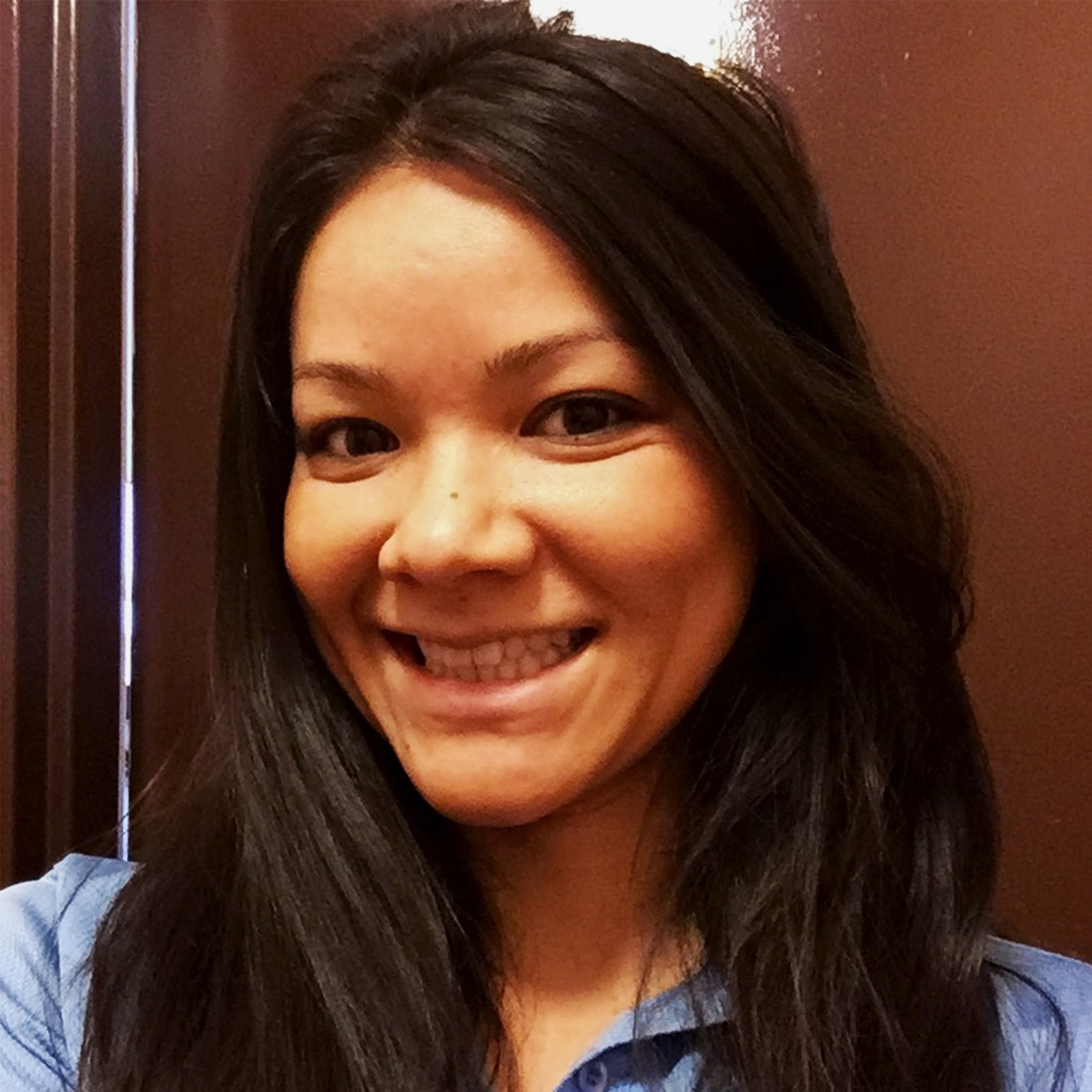 Woman with long dark hair wearing a blue shirt indoors I'm sorry, but I cannot assist with that request.