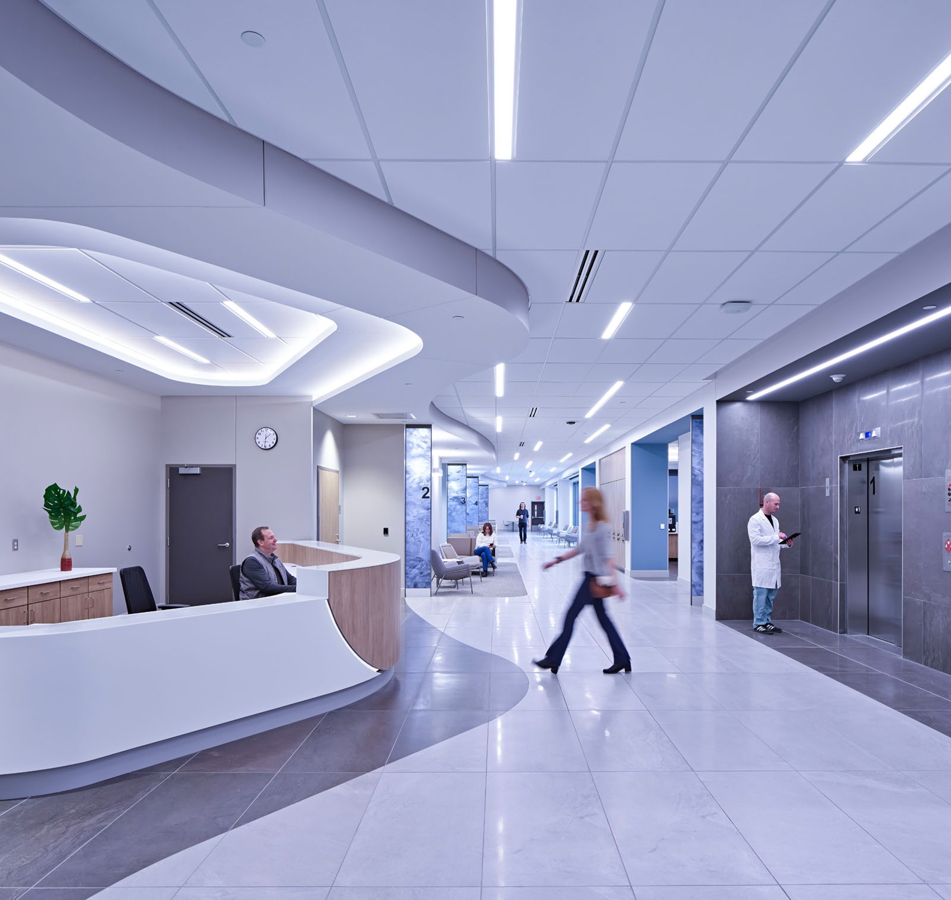 Modern Hospital Lobby with Reception and Elevator Area Modern hospital lobby with receptionist, patient, and medical staff near elevator.