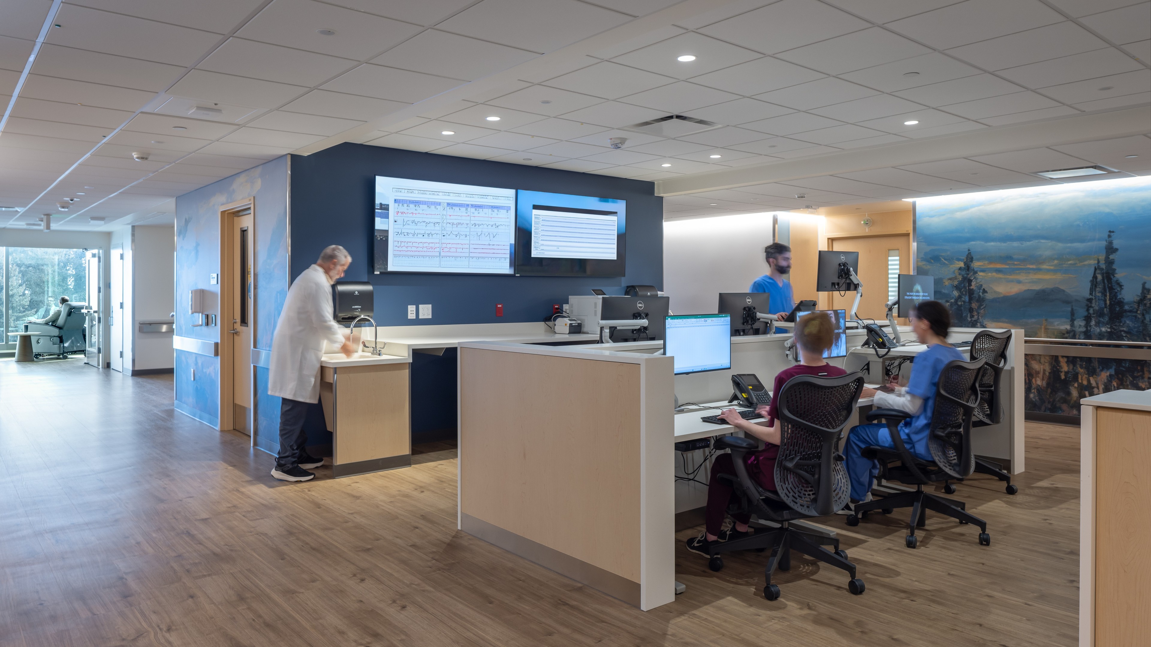 Modern hospital nurse station with medical staff working on computers and monitors.