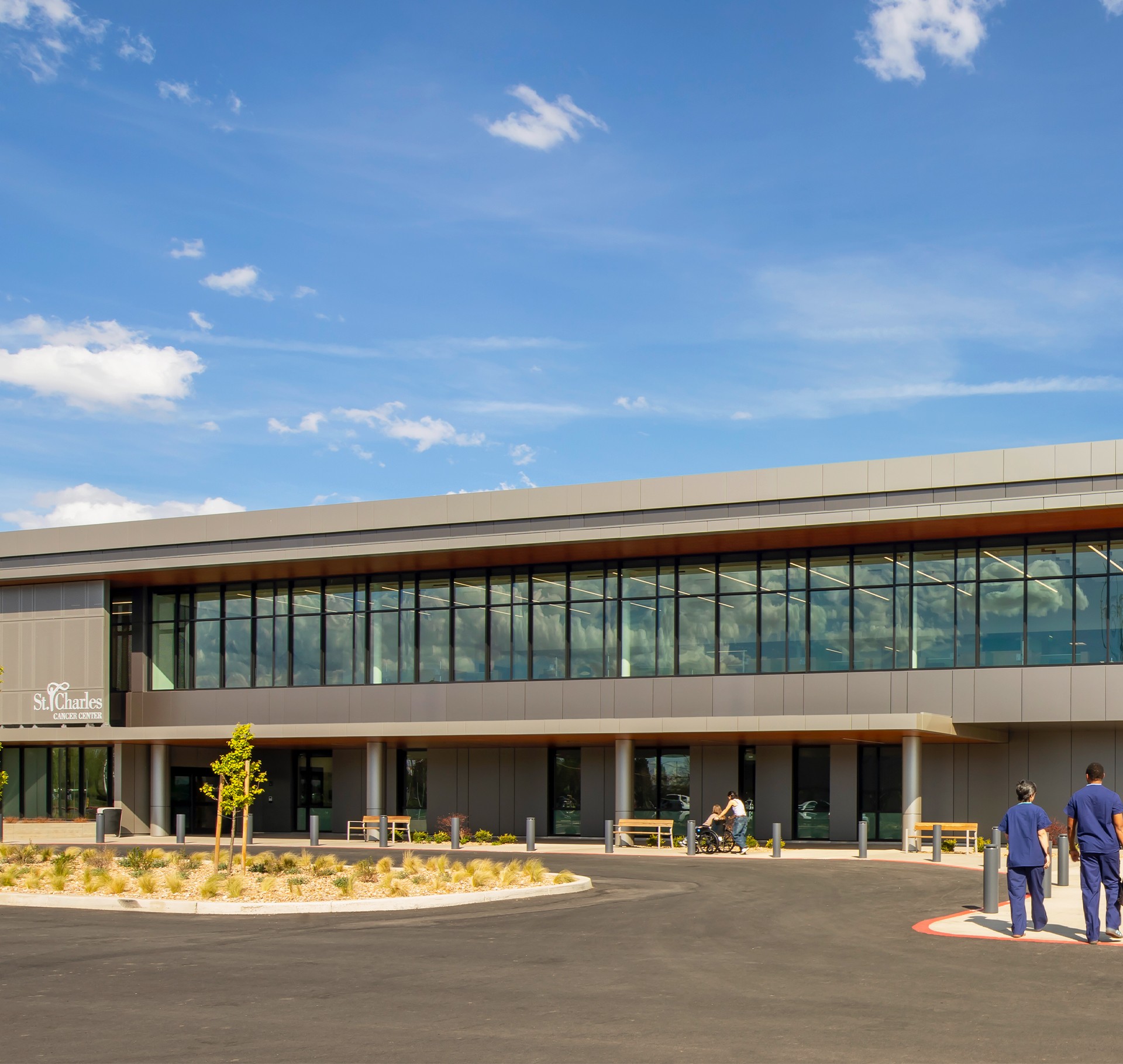 Modern St. Charles cancer center with clear skies and medical staff outside.
