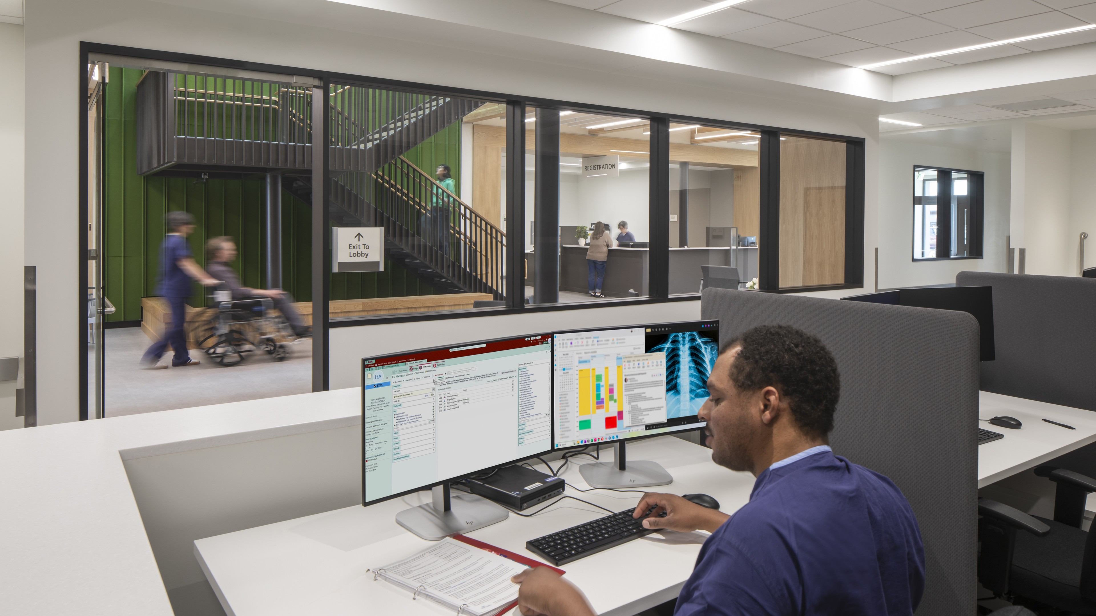 Healthcare professional reviewing patient data on dual monitors in a modern medical office.
