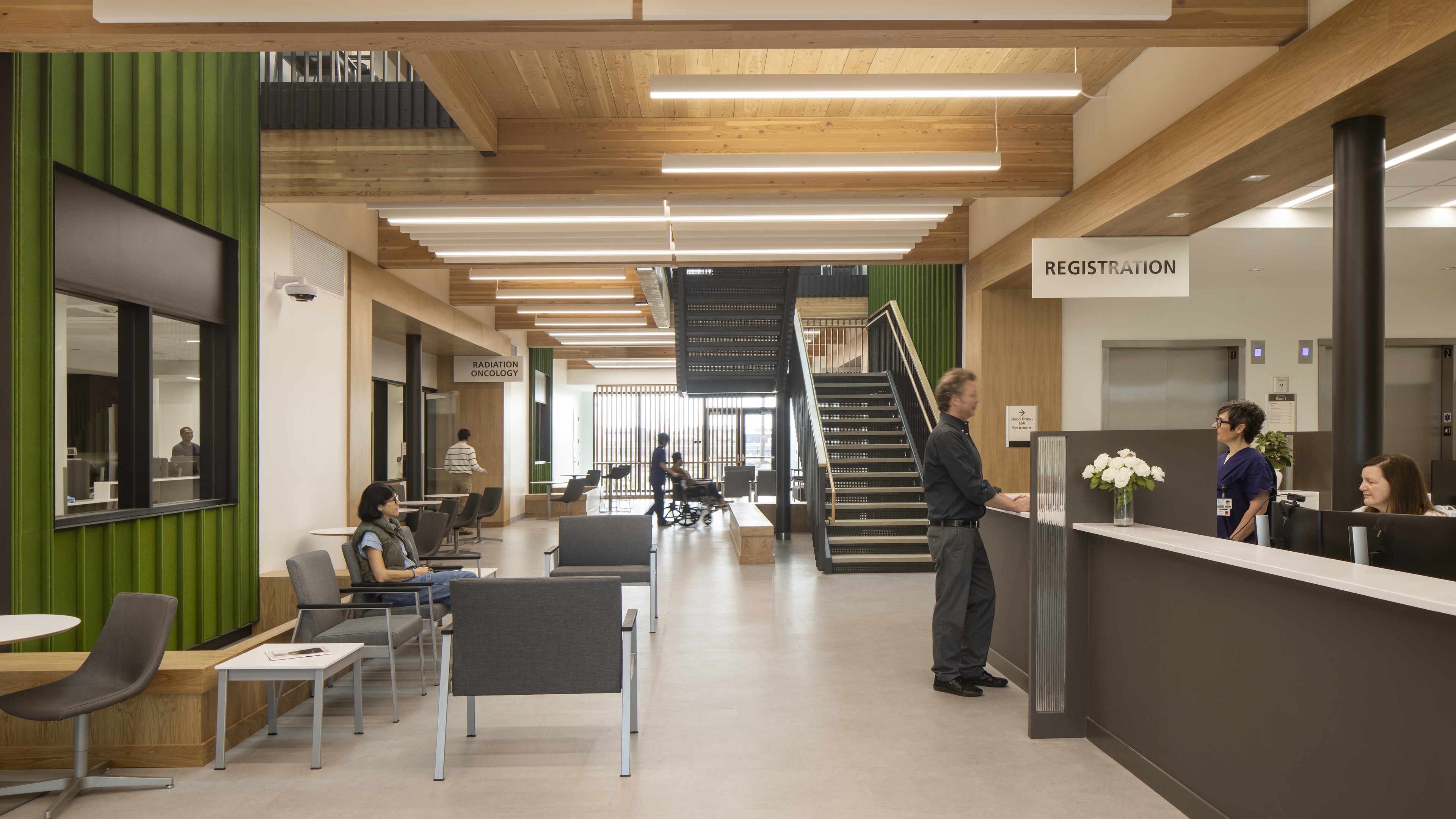 Modern medical clinic reception area with seating, staff, and patient registration desk.