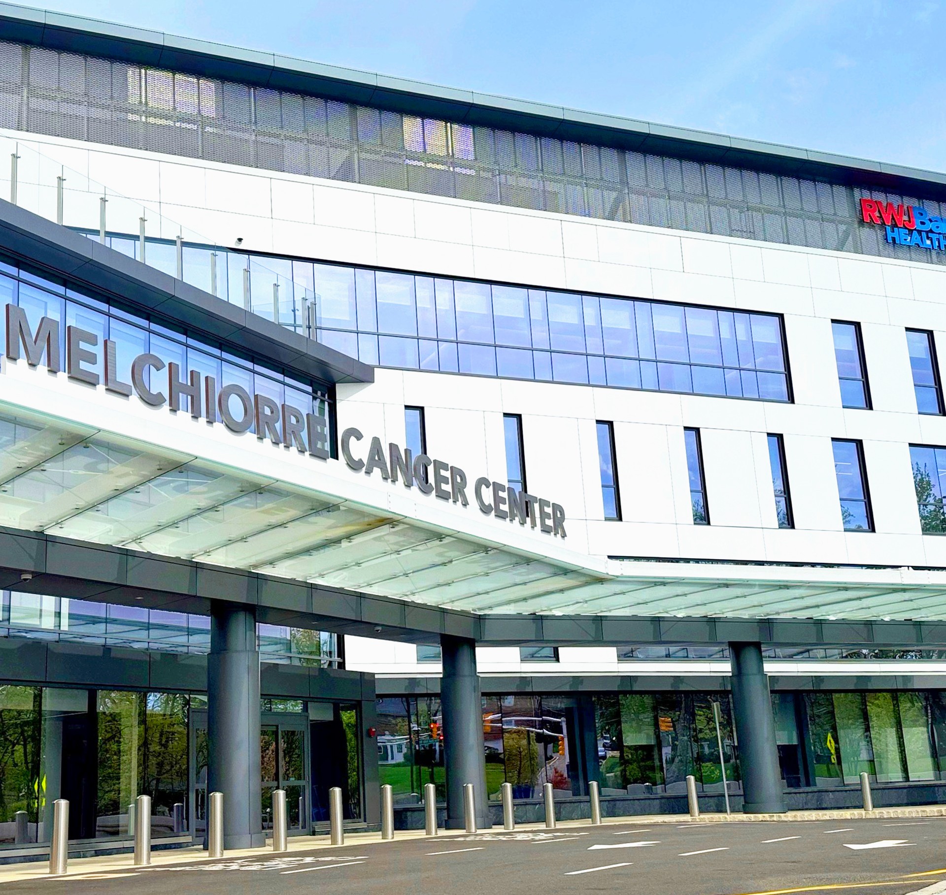 Modern Melchorre Cancer Center building with glass facade and clear blue sky.