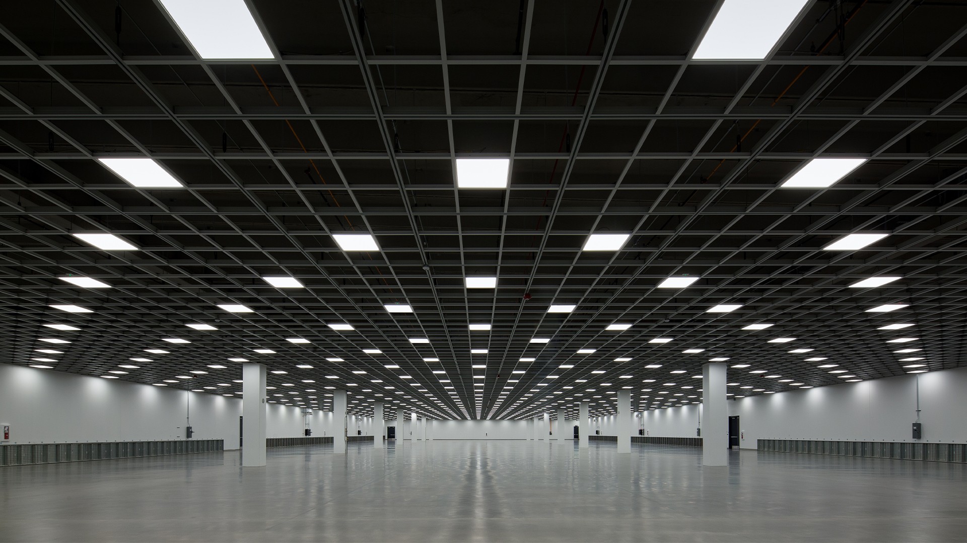Spacious, modern, grid-ceiling interior with polished floors and evenly spaced square lights.