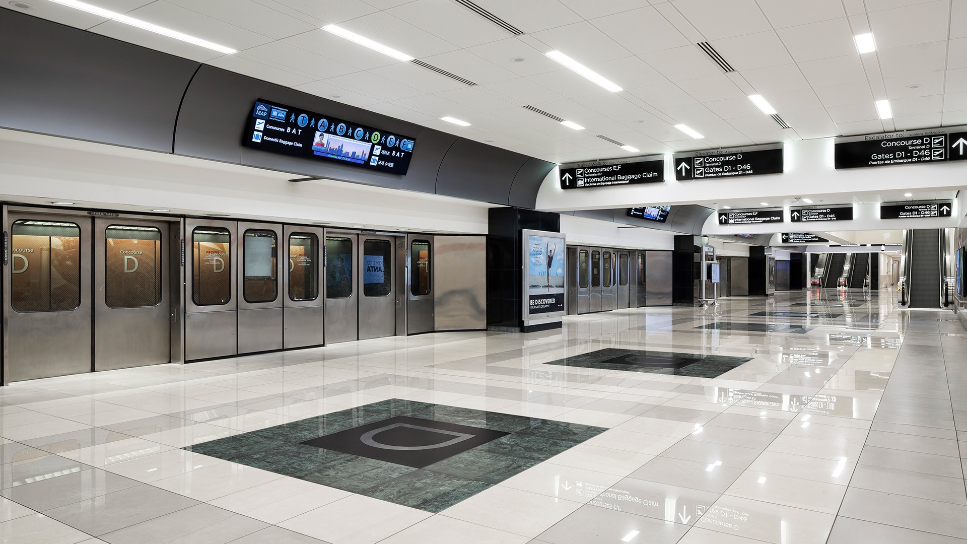 Modern airport train station with clean, polished floors and clear directional signs.