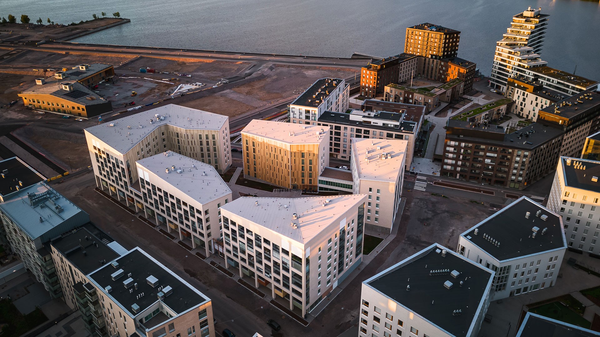 Atrain-kortteli sijaitsee meren ja kauppakeskus REDIn palveluiden läheisyydessä. Ilmakuva moderneista rantaviivan asuinrakennuksista, joissa on geometriset suunnittelut ja auringonlaskun valaistus.