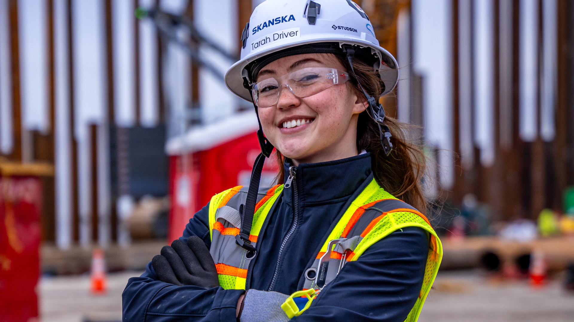 Female construction worker in safety gear at building site Construction worker wearing safety gear and helmet at an active building site.