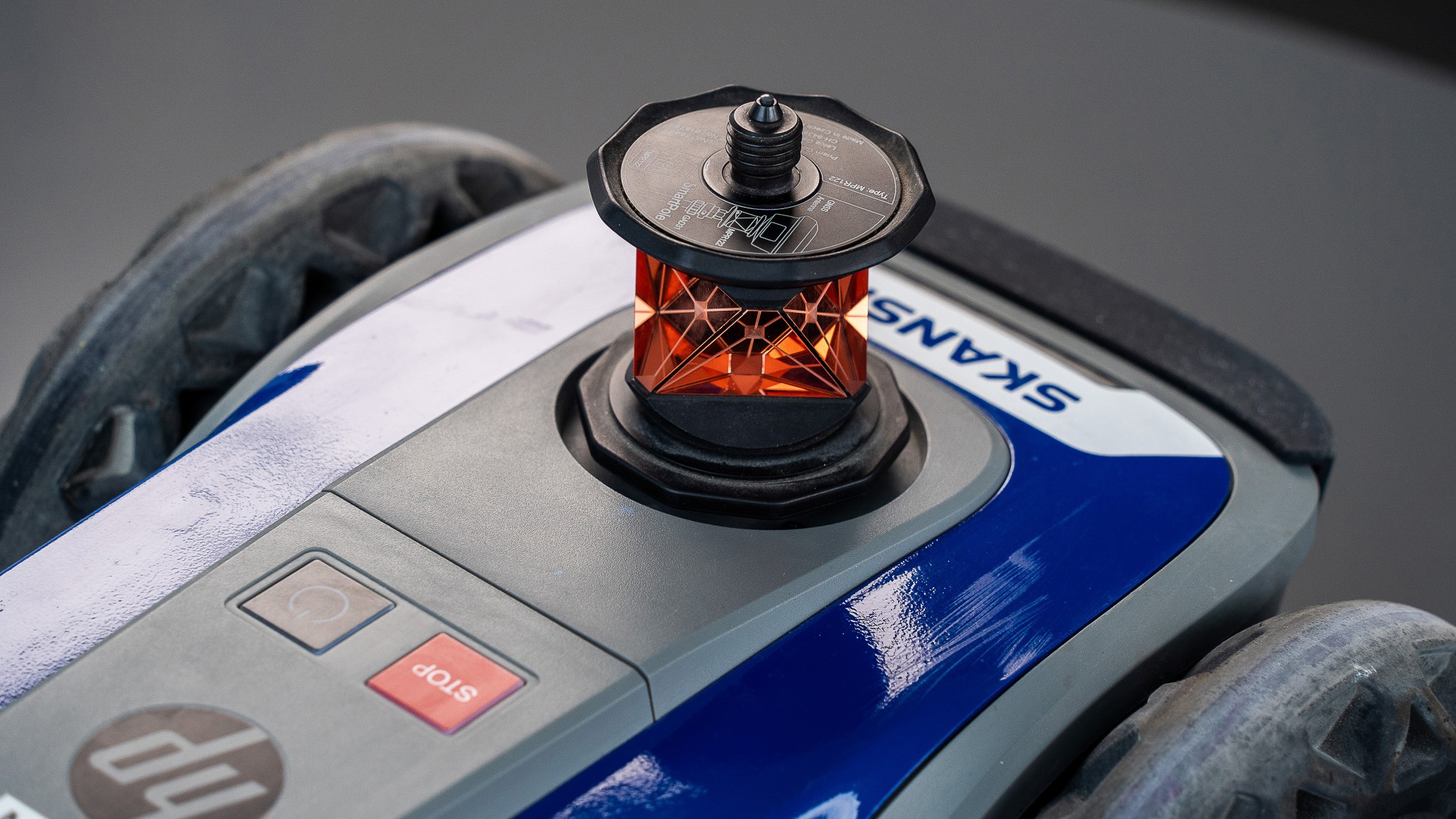 Close-up of a Skanskan robotic device with a red sensor and stop button on wheels.