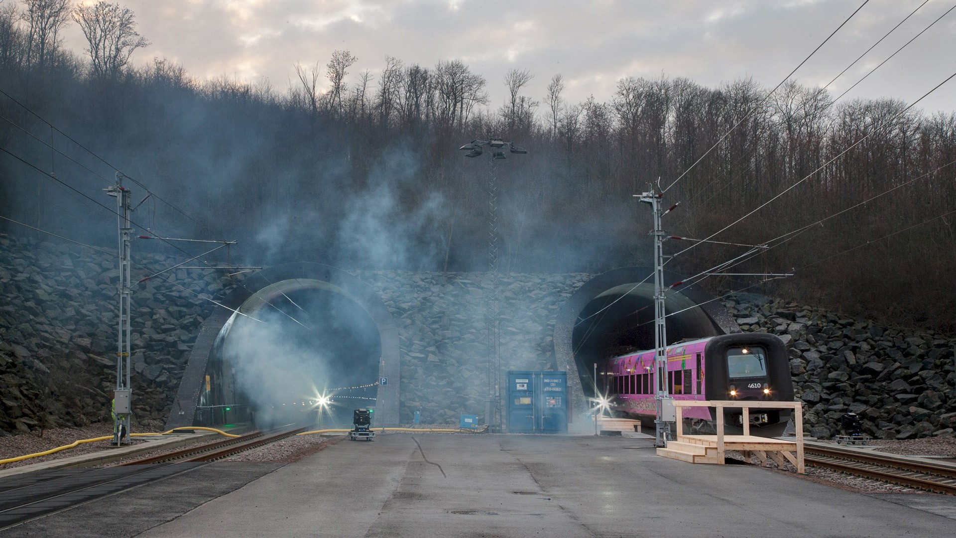 Rökprov i en järnvägstunnel med ett stillastående tåg och utrustning synlig nära ingången.