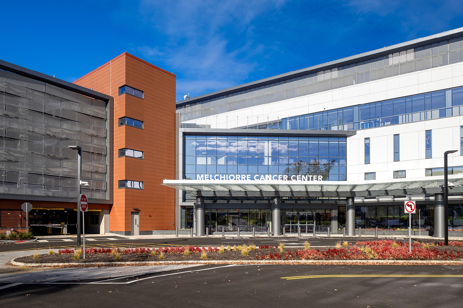 Modern Melchiorre Cancer Center building with clear blue sky and landscaped entrance.