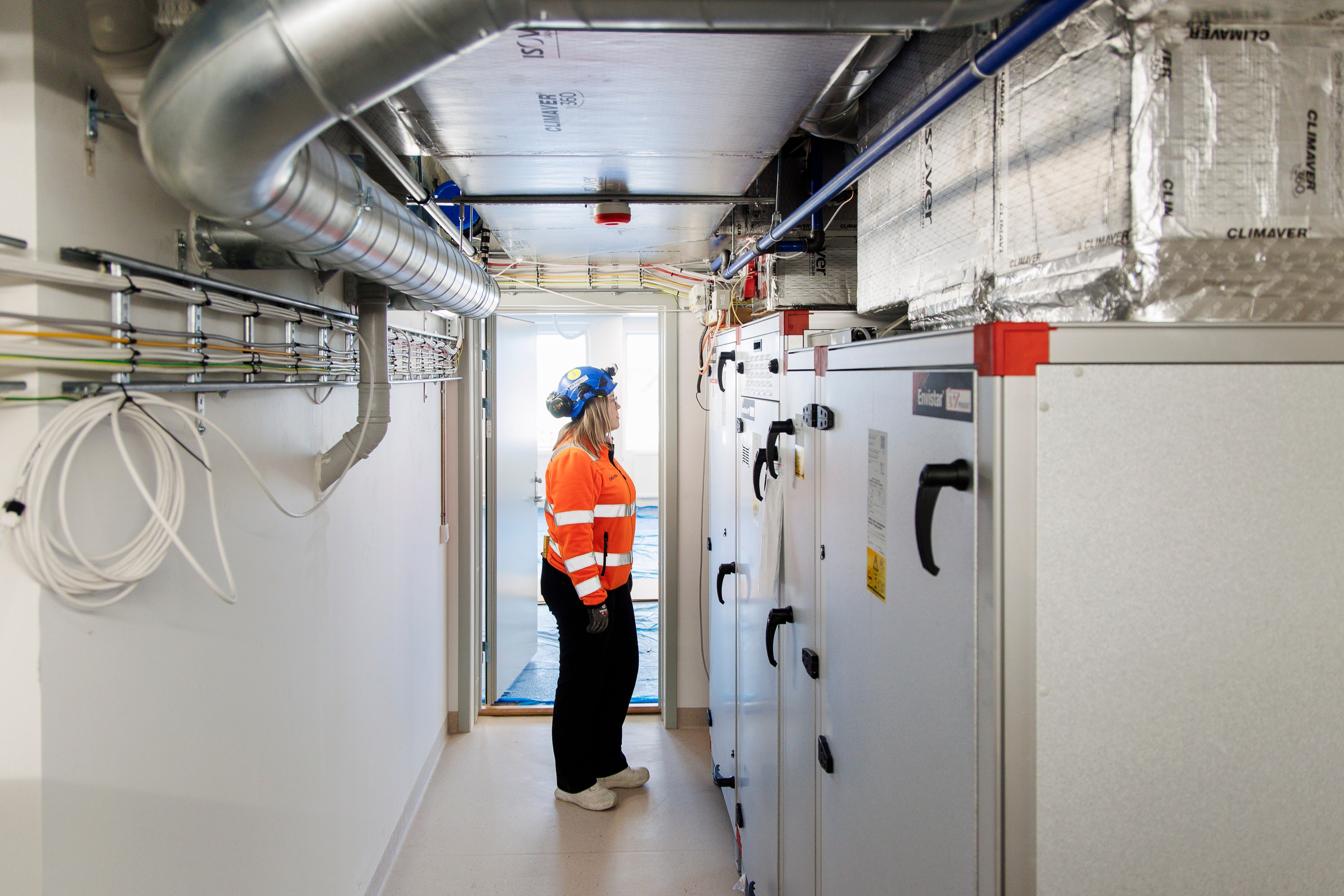 Arbeider i verneutstyr som inspiserer industrielt HVAC-utstyr i et rent teknisk rom.