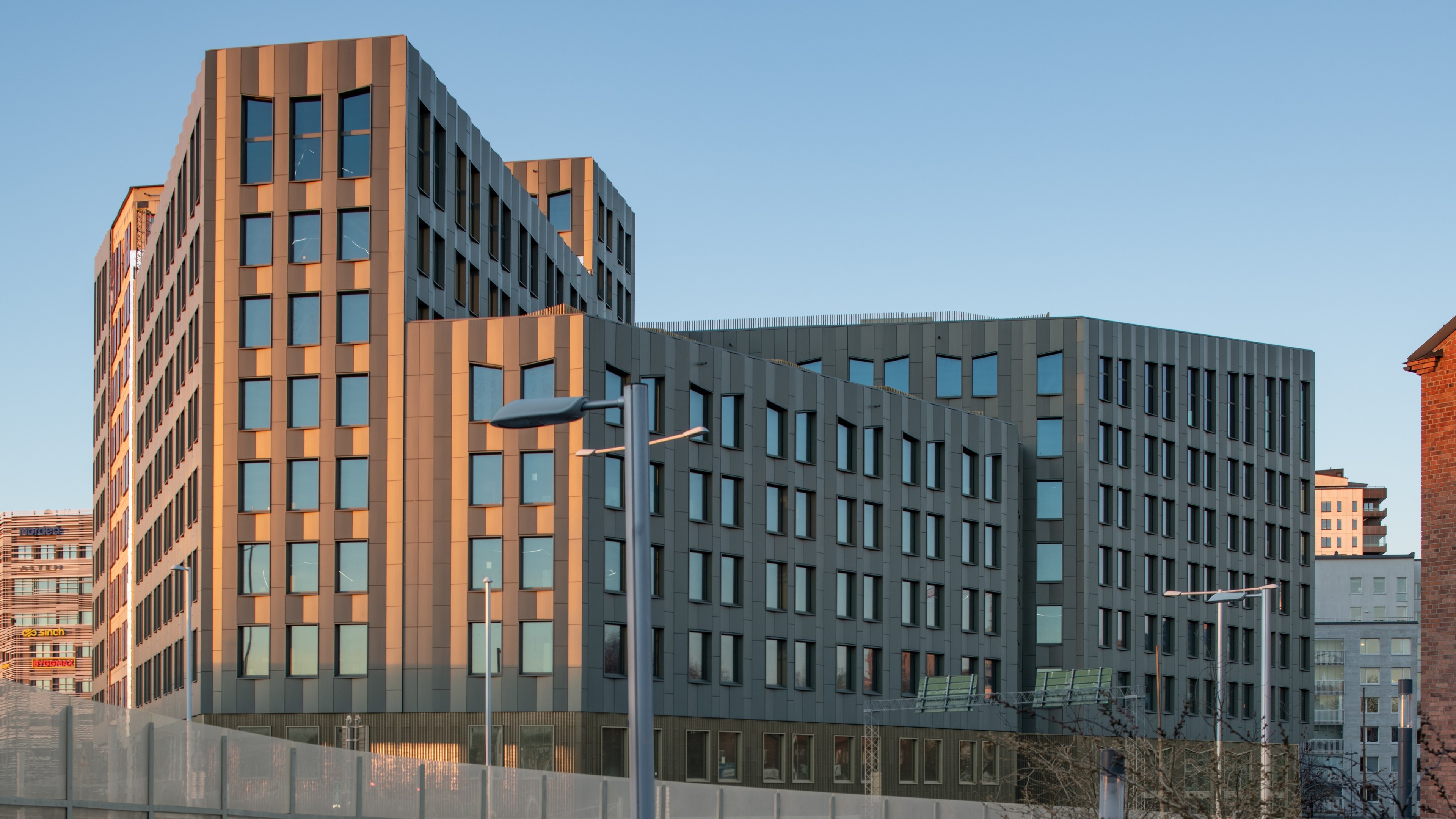 Kontorsbyggnaden Olivin med stora fönster under klar blå himmel vid solnedgång.