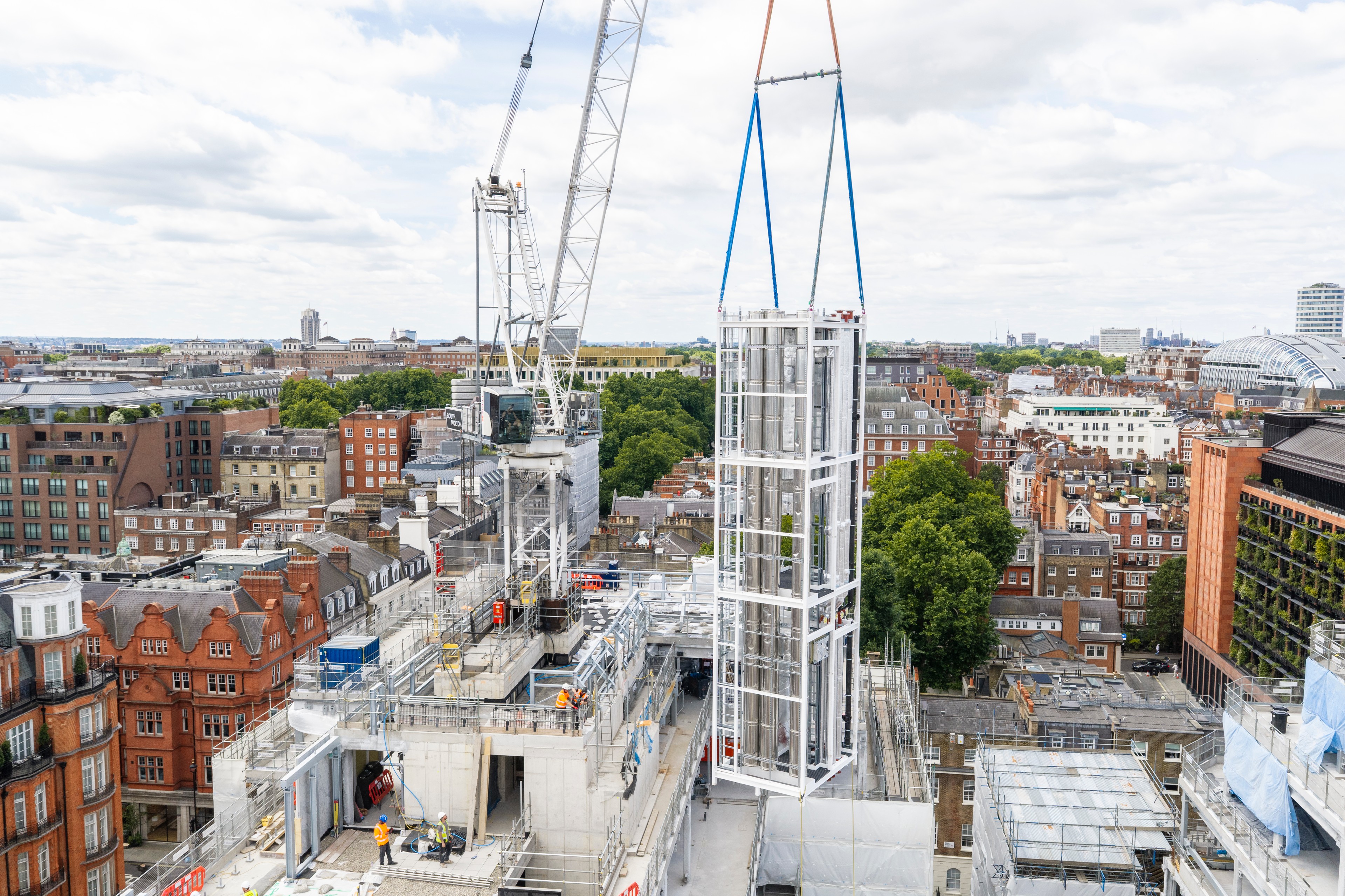 Construction crane lifting MEP riser into position. Construction crane lifting a large MEP riser on a city building site.