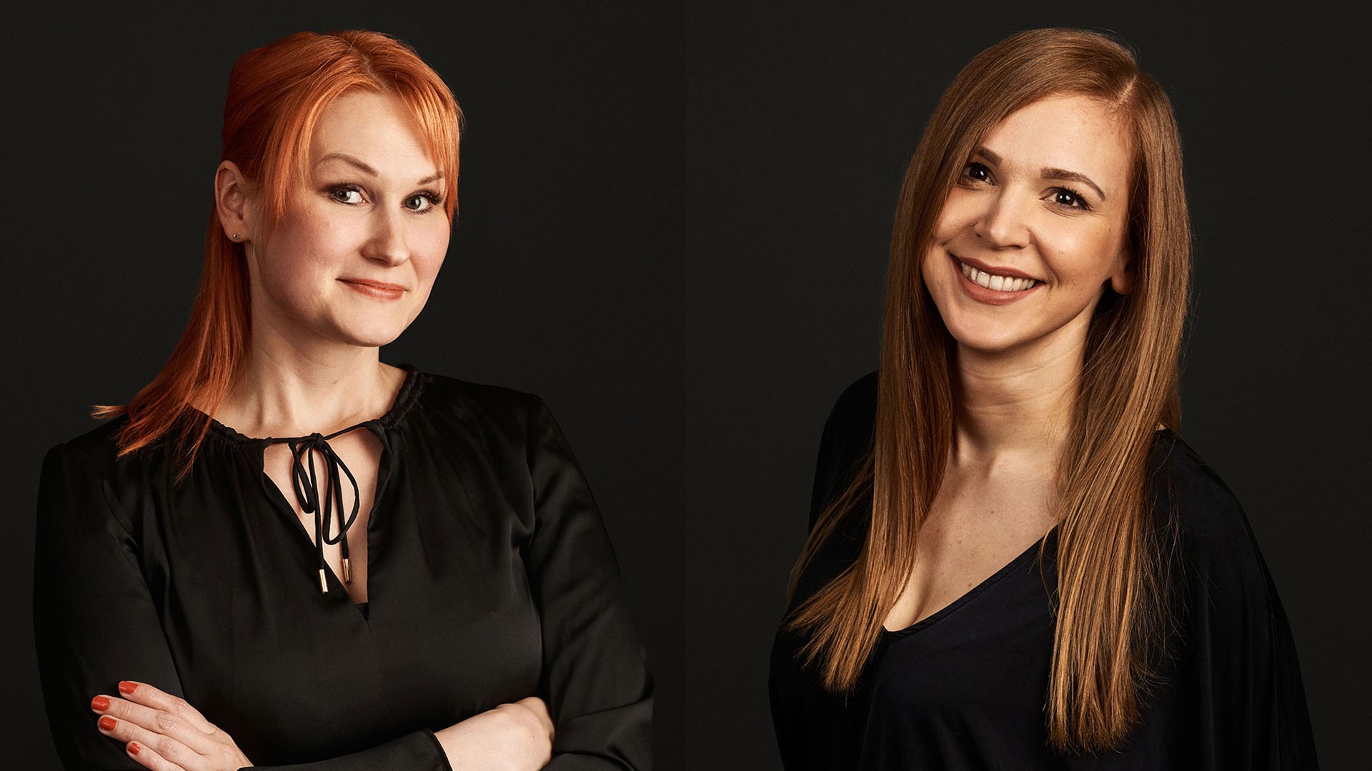Professional Women in Elegant Black Attire Two women with long red hair wearing black tops against a dark background.