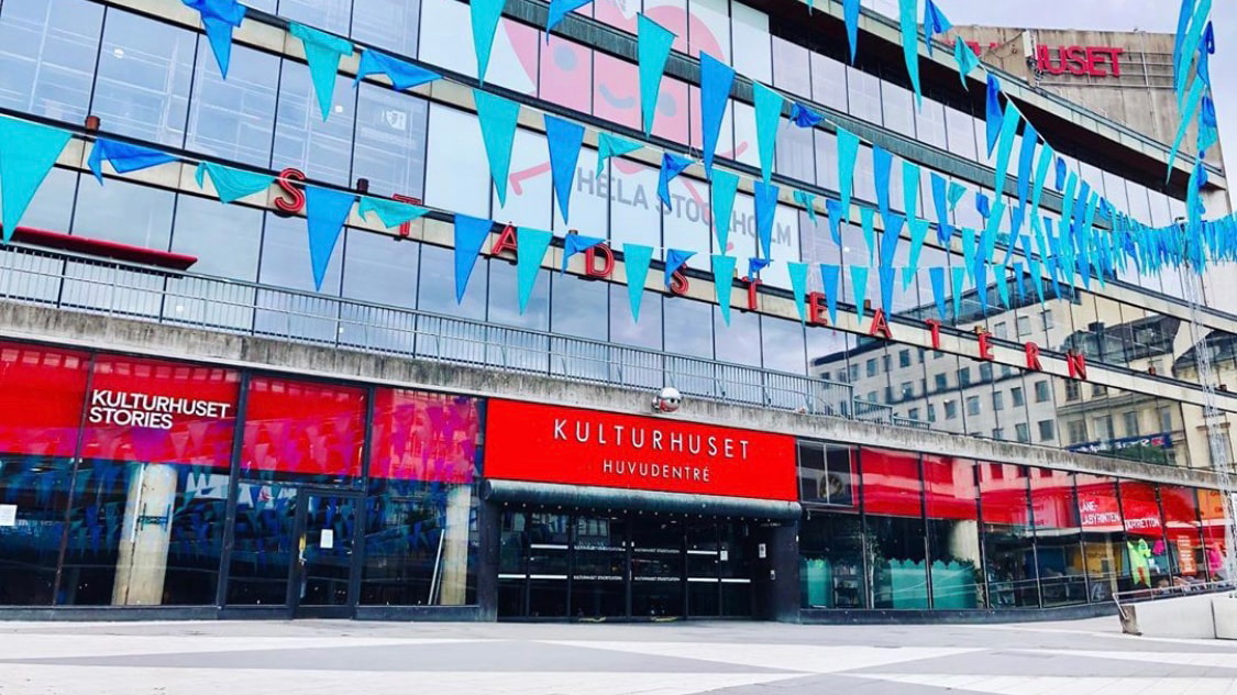 Kulturhuset Stadsteatern i Stockholm, med blåa flaggor och livfulla röda skyltar.