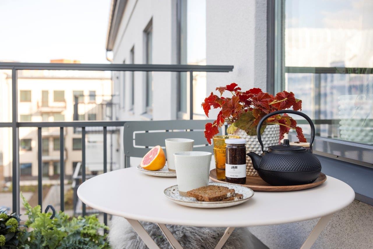 Balkong med dukat runt bord och utsikt över innergård samt grannhus.