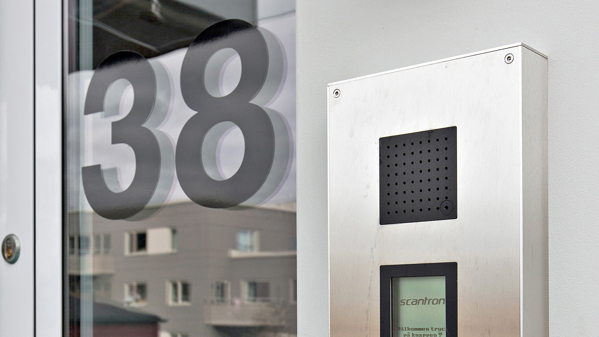 Södra Brottkärr Dörr med nummer 38, med ett Scantron porttelefonsystem på en modern byggnadsfasad.
