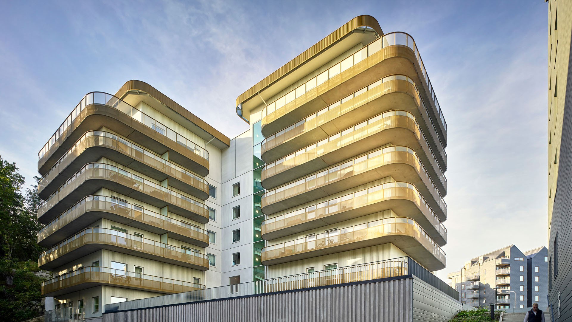 Modern lägenhetsbyggnad med runda balkonger och glasdetaljer under en klar himmel.