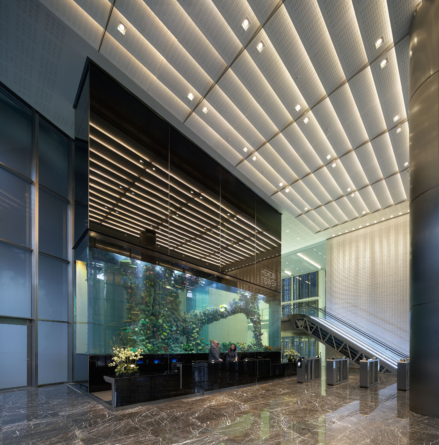 Heron Tower Modern lobby with high ceilings, reflective surfaces, an aquarium, and sleek design elements.