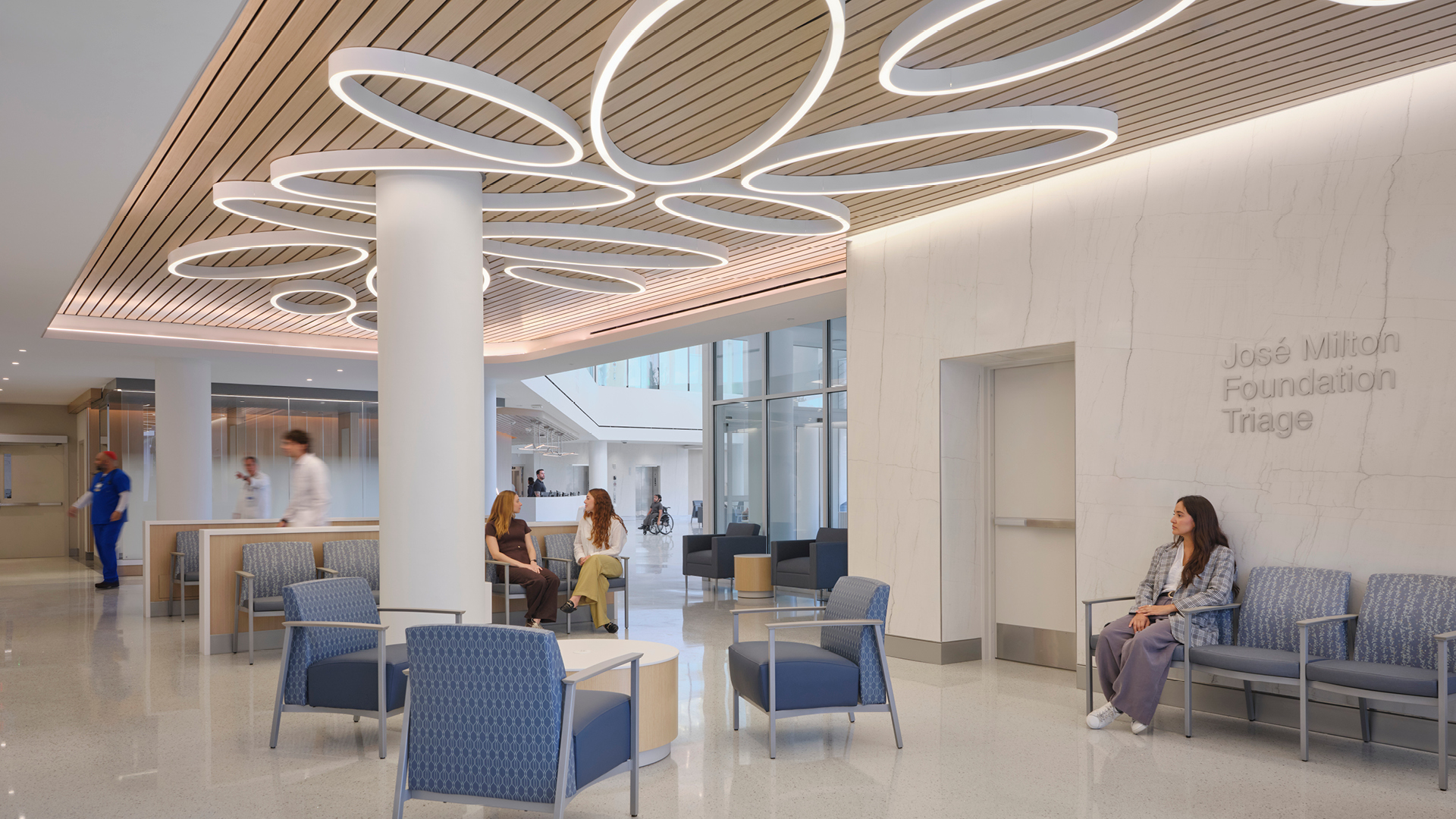 Modern Hospital Waiting Area with Stylish Seating and Lighting Modern hospital waiting area with blue chairs, wooden ceiling, and bright lighting.