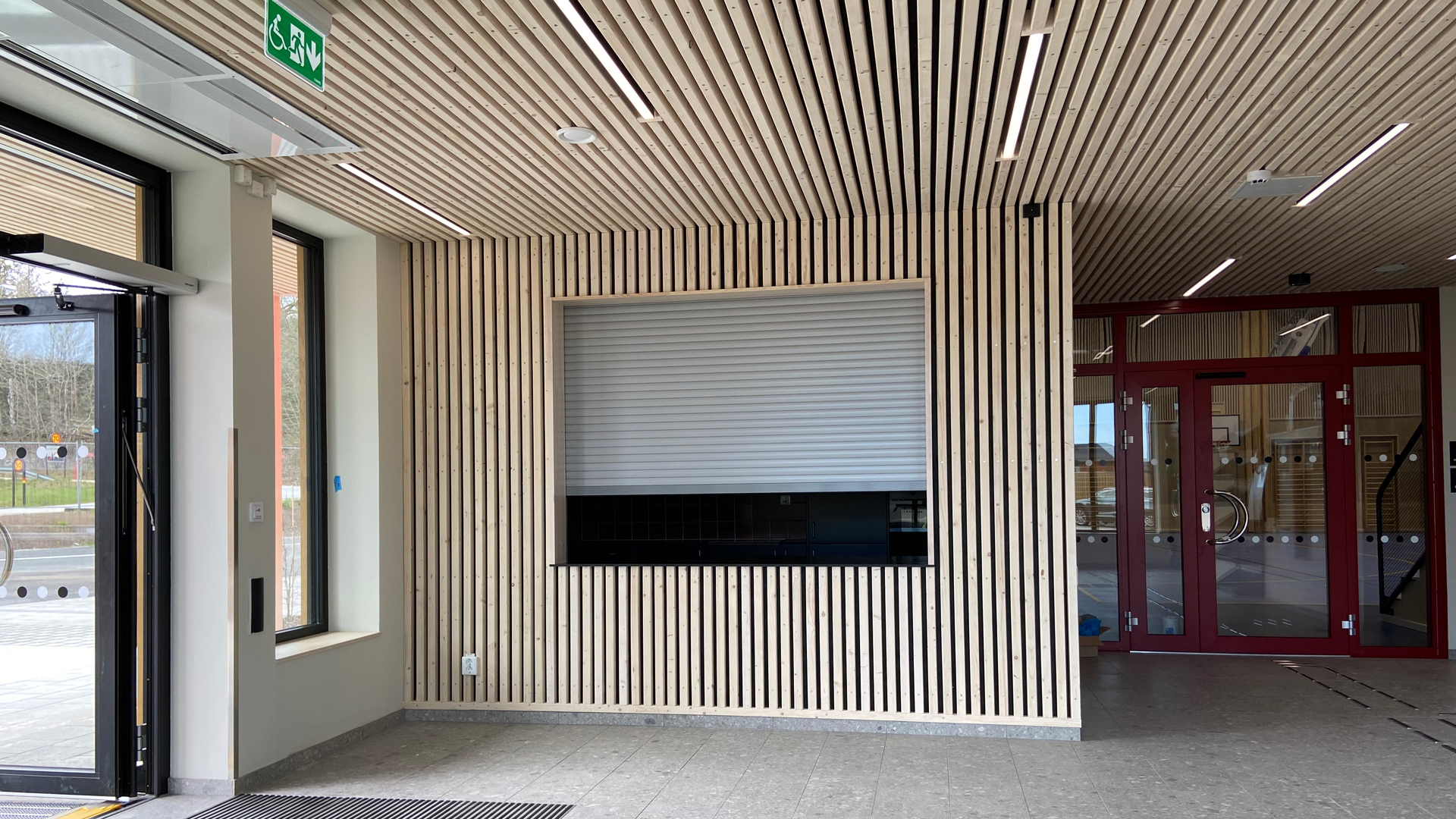 Idrottshallen har många naturliga träytor och materialval Listerby idrottshall entredelen med träpanel.
